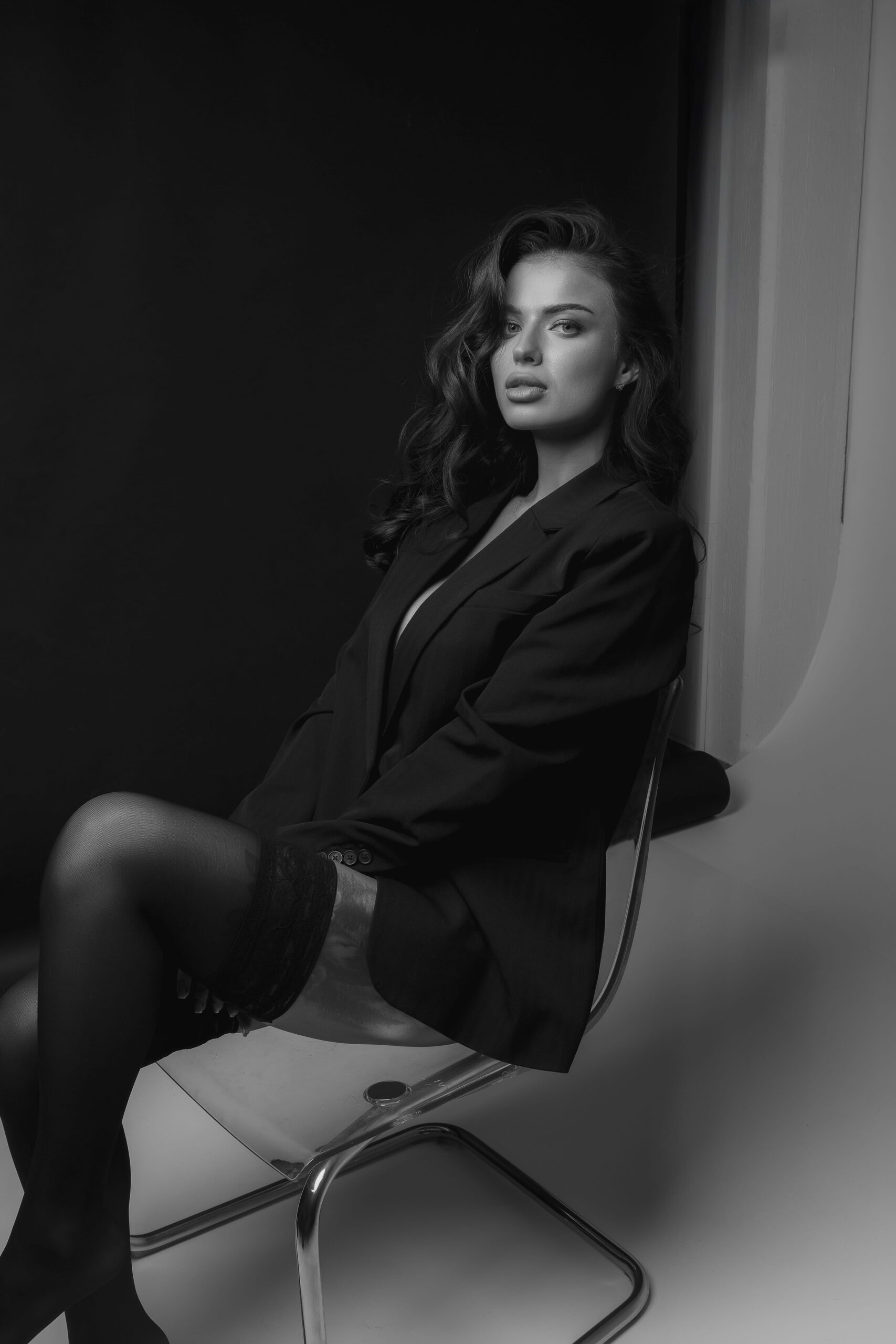 A woman in a black dress leaning against a studio wall