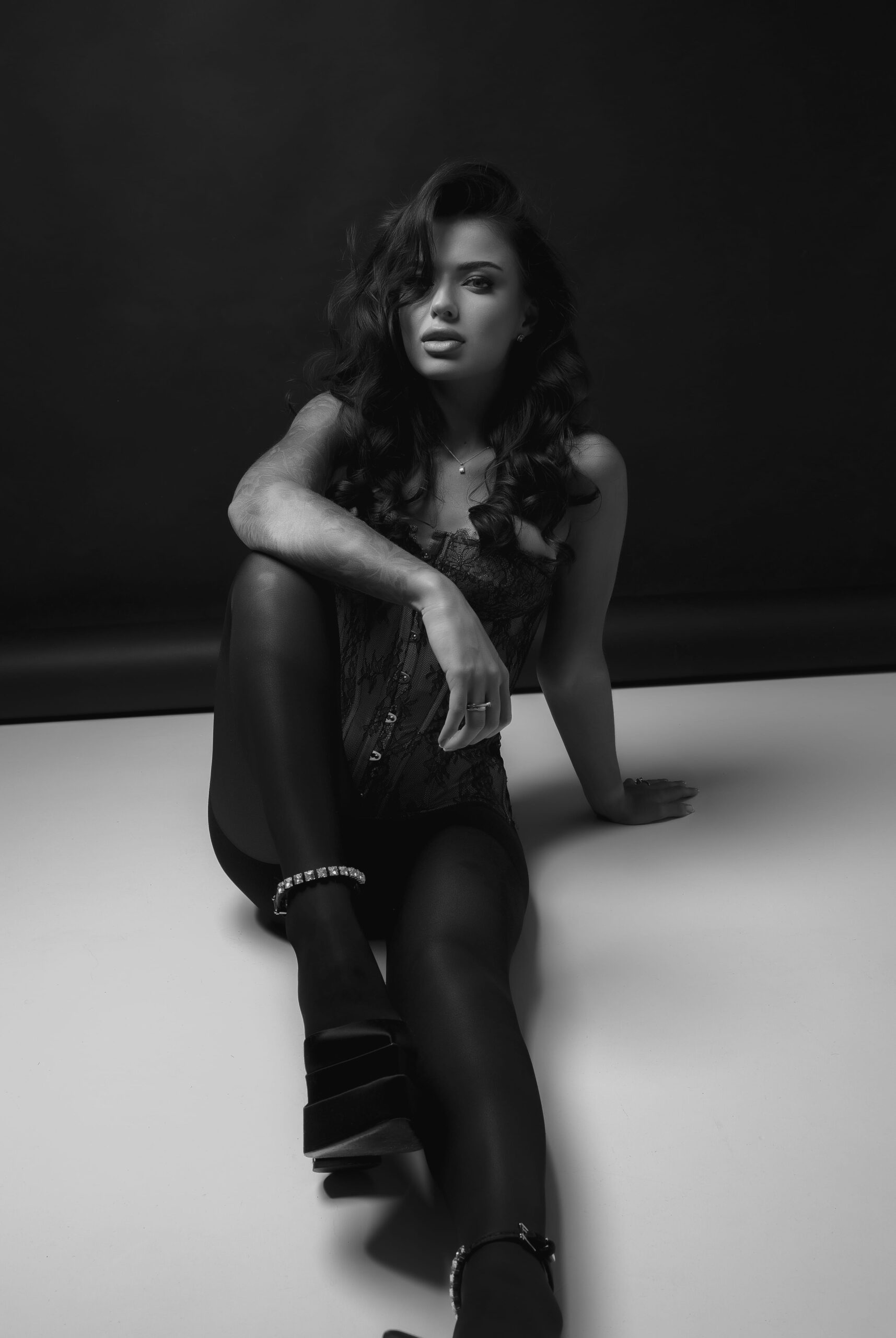Black and white portrait of a woman seated against a dark backdrop