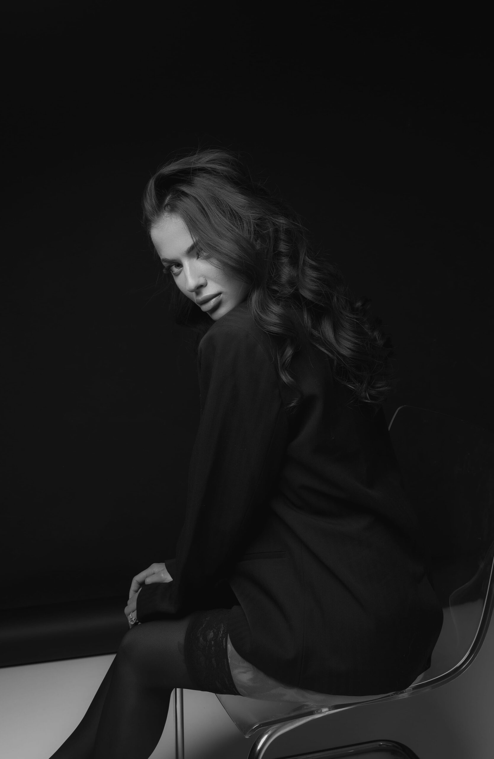 Black and white seated portrait against a dark studio backdrop