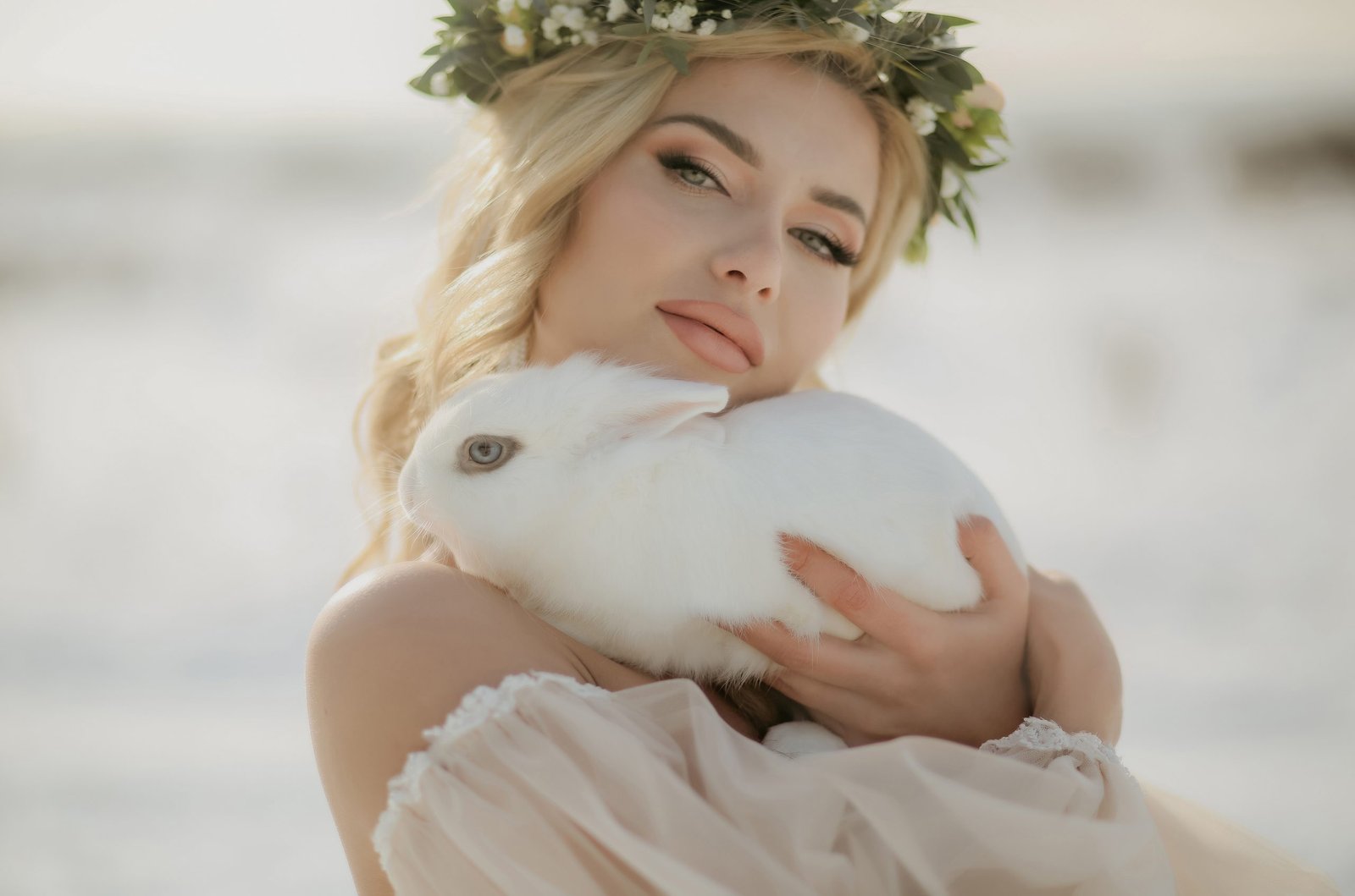 A woman wearing a flower crown holding a white rabbit